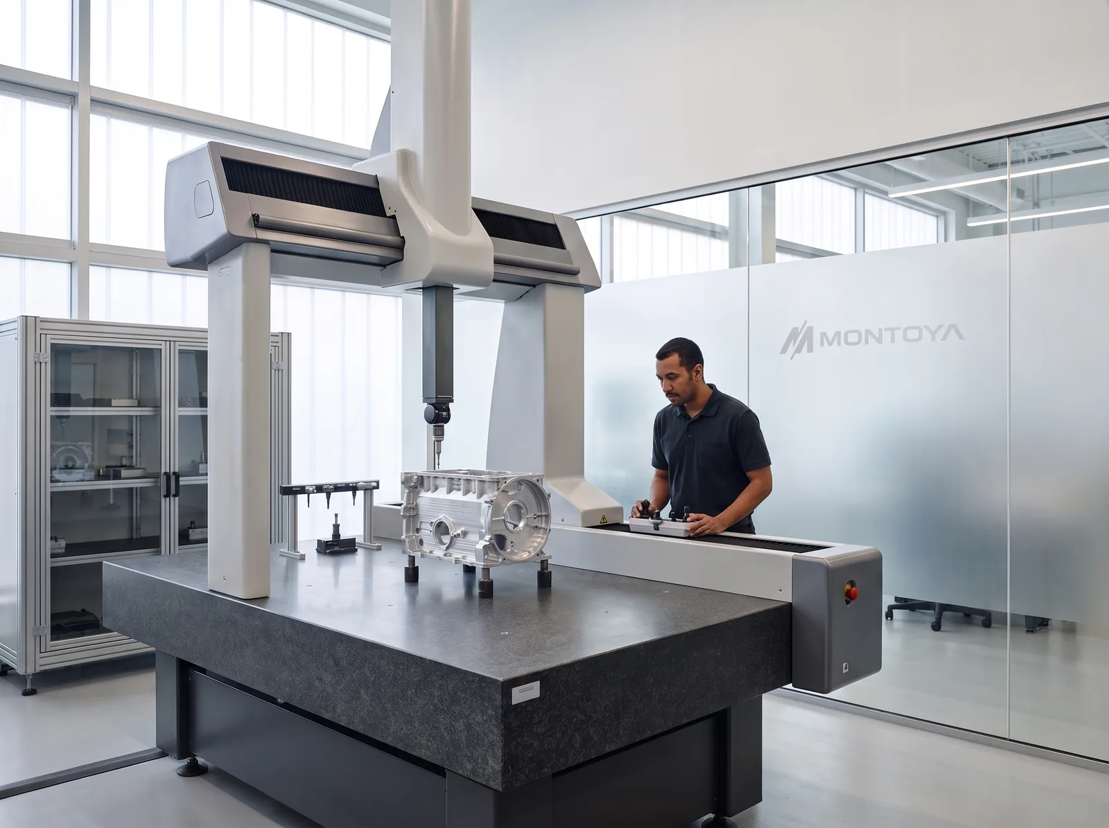 Imagen conceptual de un laboratorio de calidad con una máquina de medición por coordenadas y el logotipo de Montoya grabado en el vidrio.
